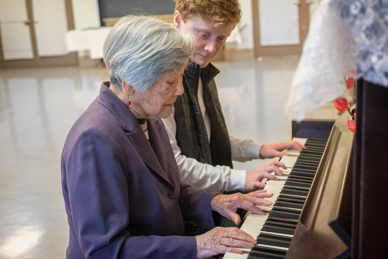 Senior Woman Playing Piano with Young Man