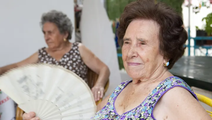 elderly woman holding hand fan